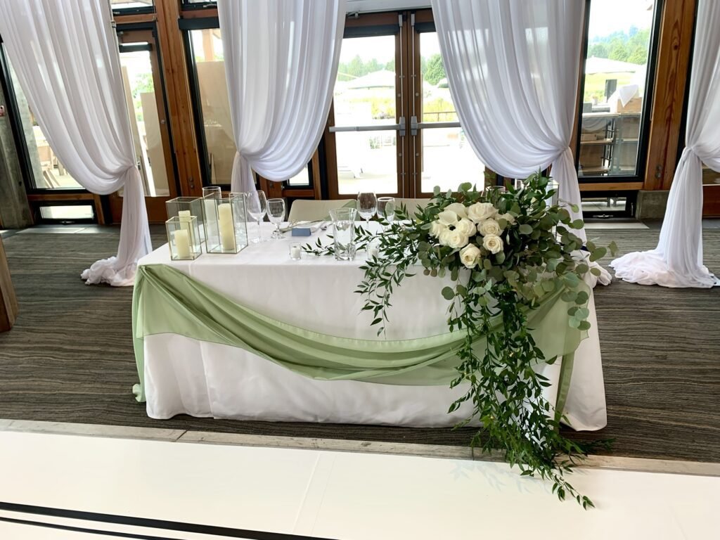 Wedding head table flowers with roses and flowing greenery