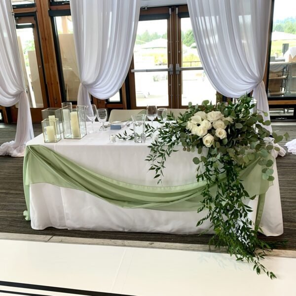 Wedding head table flowers with roses and flowing greenery