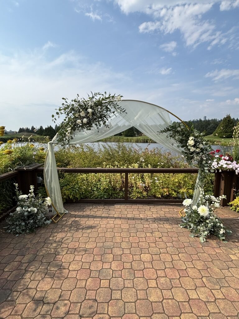 Wedding arch decorated with roses and greenery, created by a Surrey wedding florist for an outdoor ceremony.