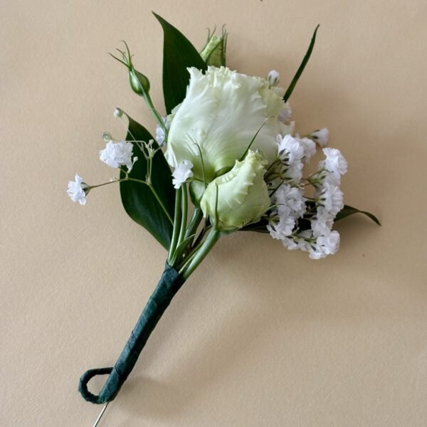 Groom’s boutonniere featuring a white lisianthus, babys breath and foliage.