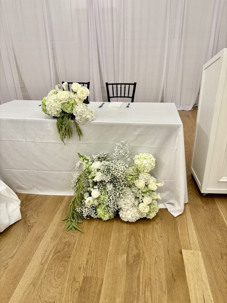 Sweetheart table decorated with modern white and green florals by a Surrey wedding florist for an elegant reception.