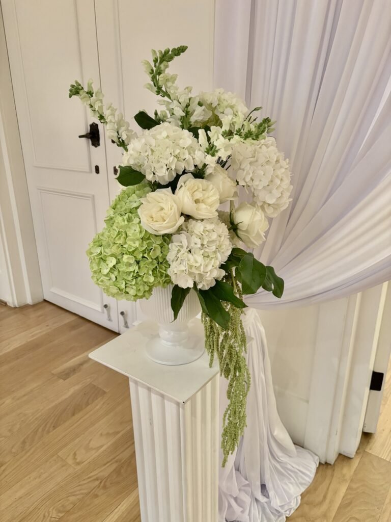 Large modern white and green pedestal floral arrangement with roses and greenery, crafted by a Surrey wedding florist