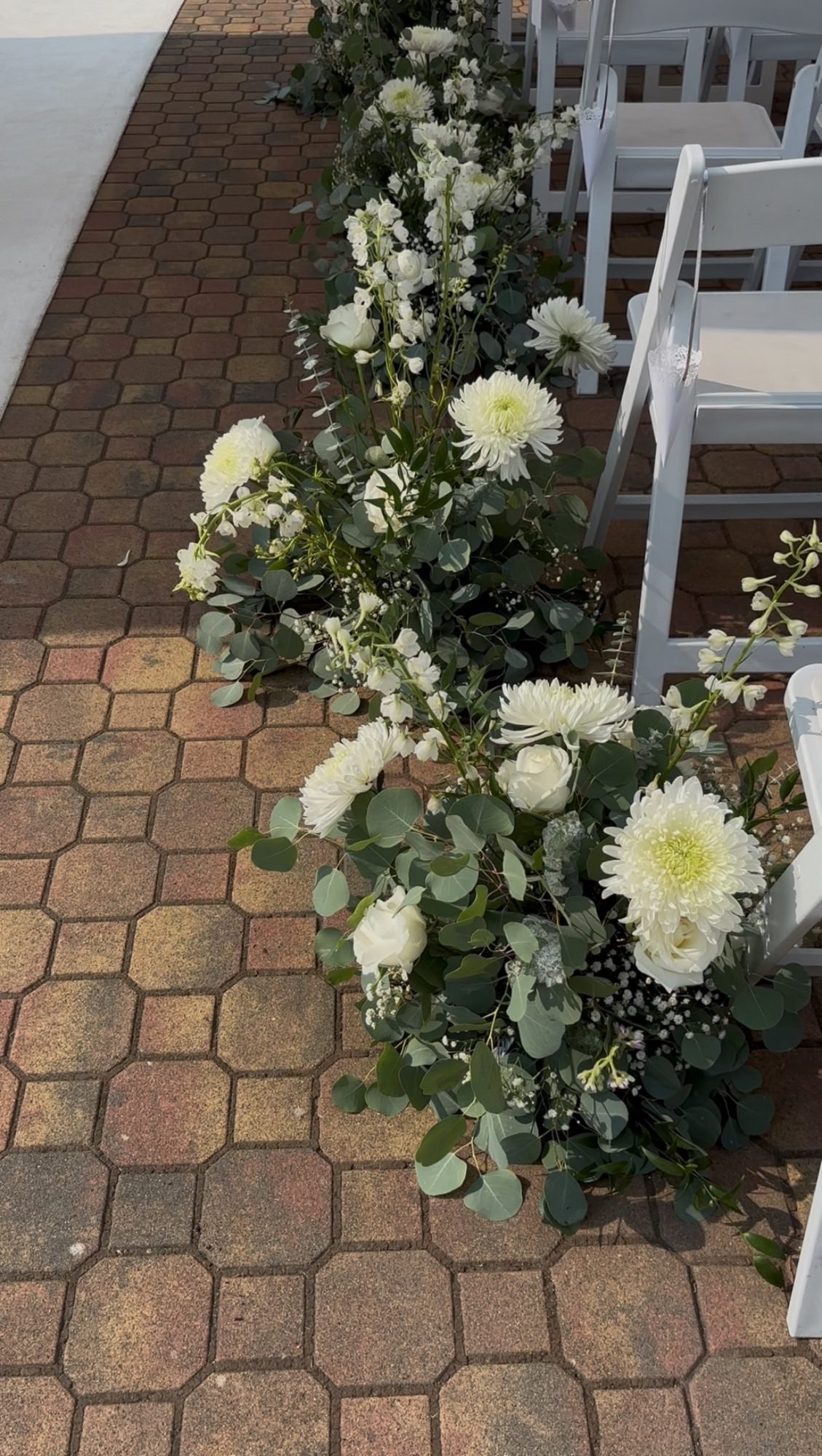 Modern white and green aisle floral arrangements designed by a Surrey wedding florist, lining the ceremony walkway