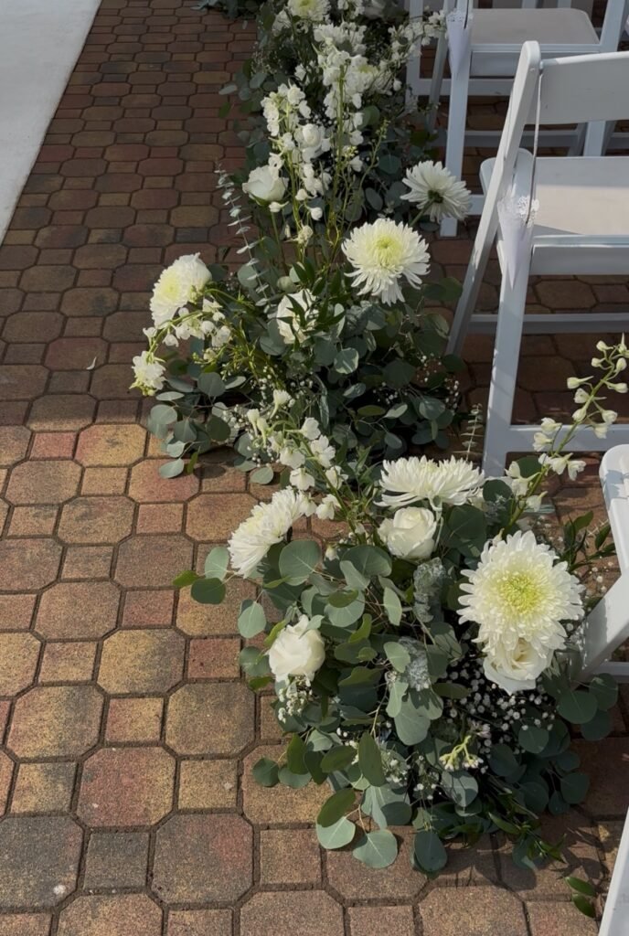 Wedding aisle piece featuring white blooms and natural greenery in a garden style